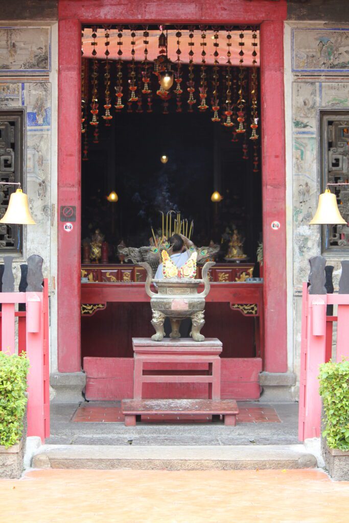 A worship altar inside Kian An Keng Shrine in Kudeejeen, Thonburi, Bangkok, with incense and lanterns symbolizing peace and devotion.