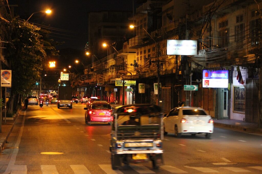 Street scene at night in Bangkok, Thailand, featuring city lights and bustling streets.