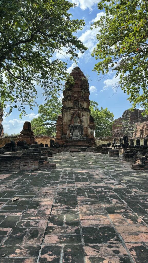The ruins of Wat Mahathat, a Buddhist temple in the Ayutthaya Historical Park, Thailand, featuring ancient stone structures and sculptures.