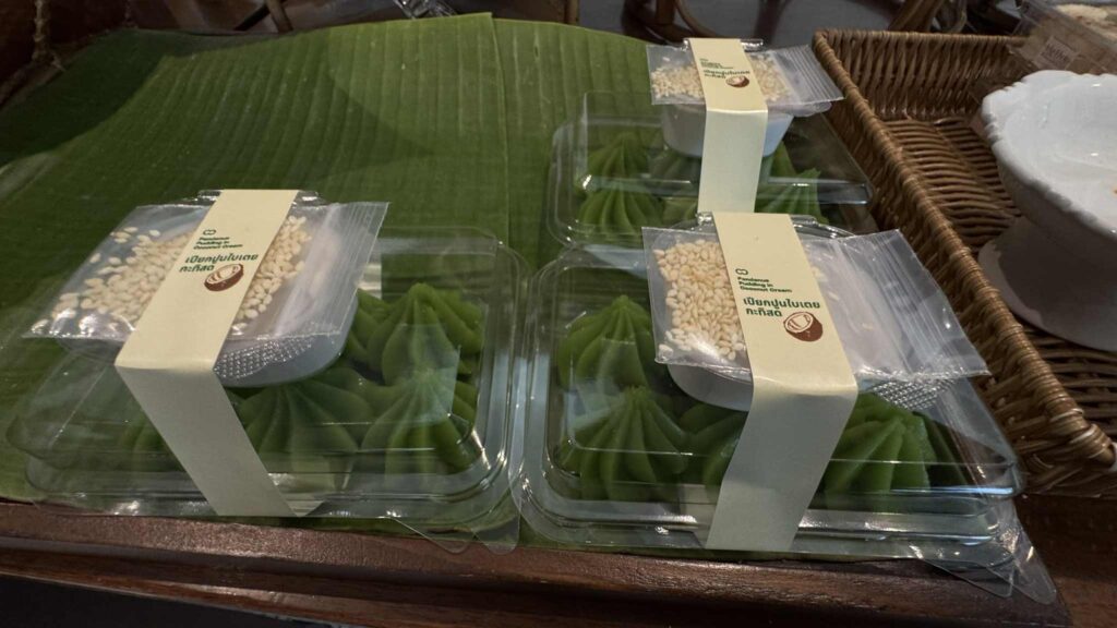 Baan Kao Nhom Nuek Poon Nai Toey – Traditional Thai dessert with crab meat wrapped in pandan leaves.